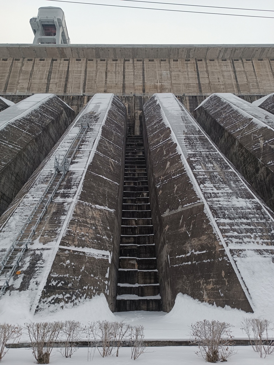 По этим водоводам в теле плотины вода падает сверху вниз и раскручивает турбины, вырабатывая электрическую энергию.