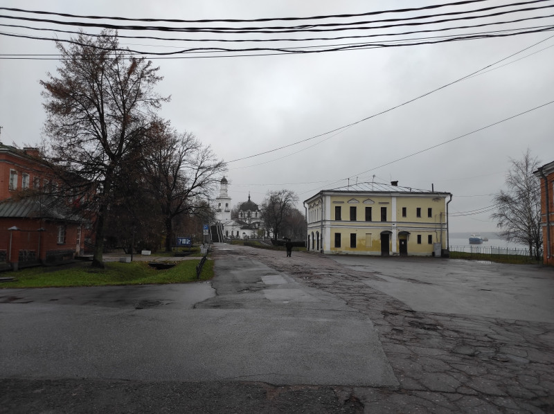 Площадь с разбитым асфальтом, дореволюционные здания и храм в перспективе