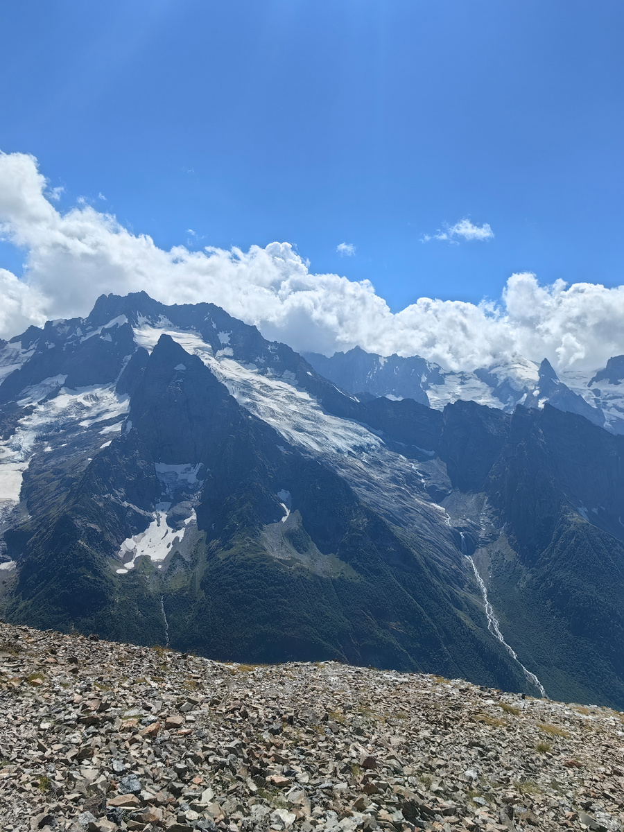 Ущелье Домбай-Ульген с верхней станции канатной дороги. Острые, будто вырубленные вершины, суровые ледники и, в правой части фото, водопад Джугутурлючат - порождение Джугутурлючатского ледника. Если подойти поближе, можно разглядеть ущелье внизу более подробно.