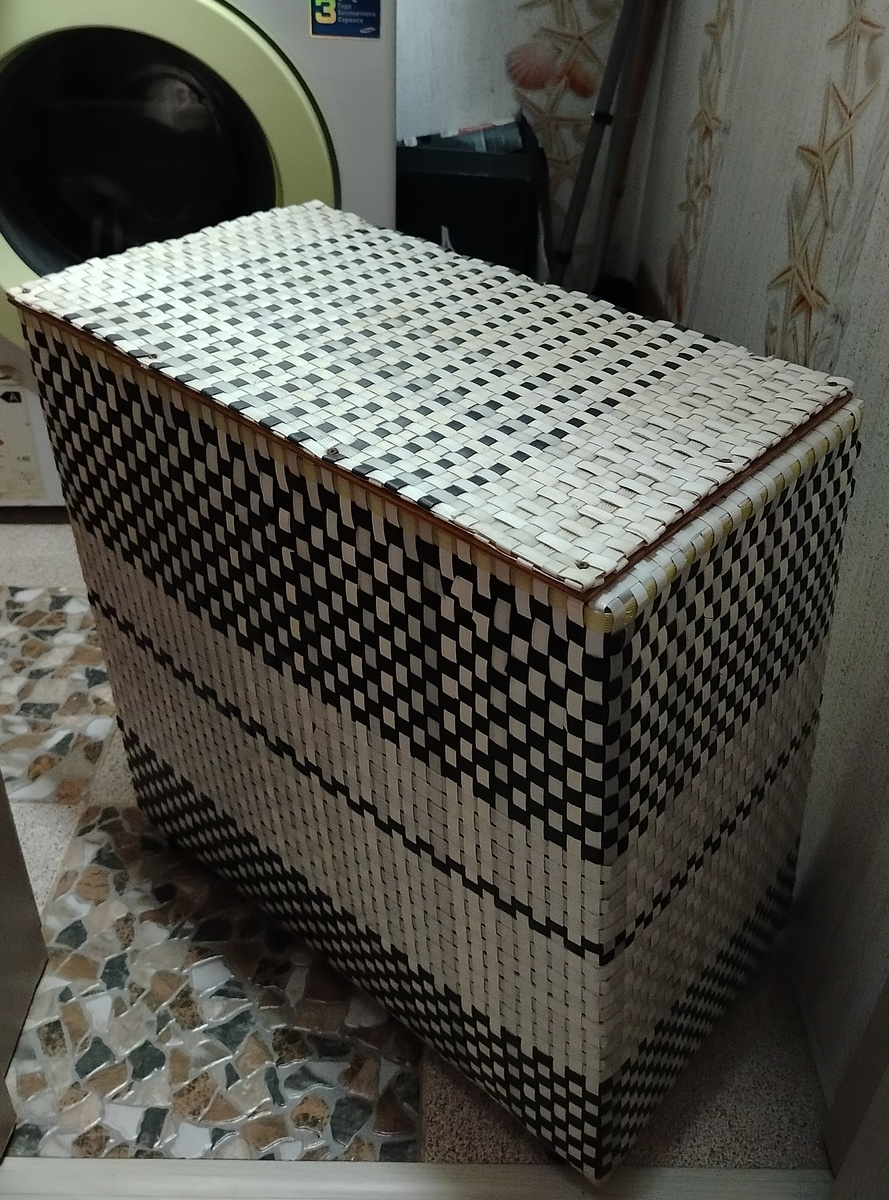 Корпус корзины представляет собой каркас (основа) из деревянных планок, который оплетался лентой. Крышка сделана из фанеры, чтоб не прогибалась, и оплетена лентой. Эта корзина служит уже много лет