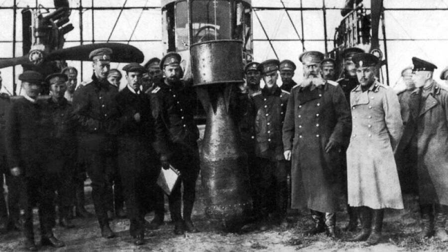 Летчики и  техники эскадры воздушных кораблей с 25-пудовой учебной бомбой. Второй  справа от бомбы в первом ряду — начальник Управления эскадры воздушных  кораблей генерал-майор Михаил Шидловский. Источник: ivak.spb.ru