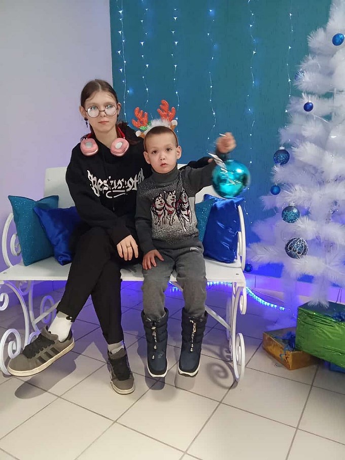 Девочка-подросток и мальчик с новогодней игрушкой