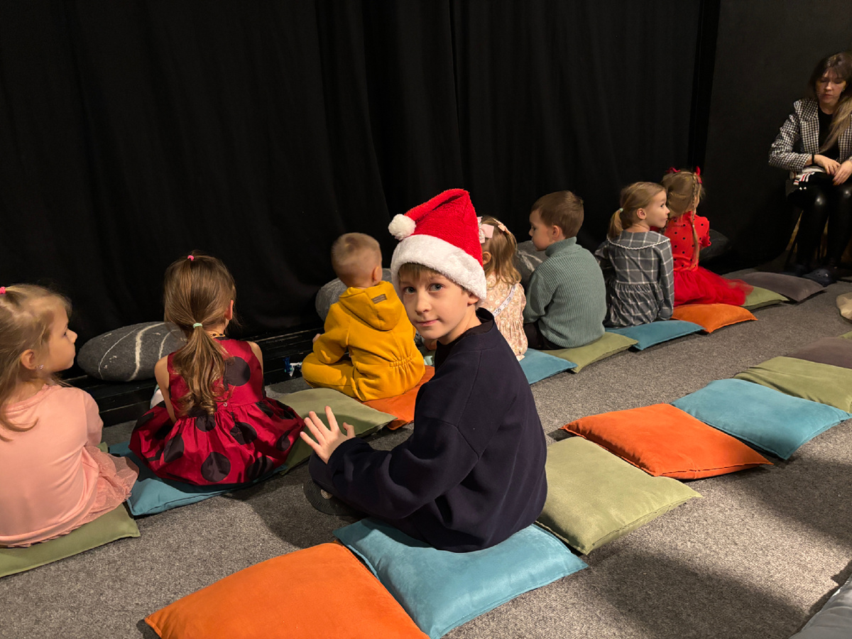 Фото автора. Дети сидят на подушках у самой сцены 