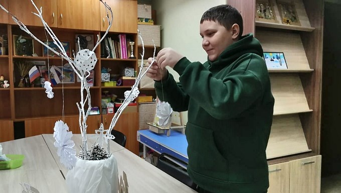 Мальчик украшает новогоднюю композицию