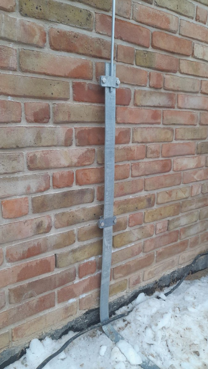 Рис.1 Крепление на кирпичной стене вывода заземляющего проводника (полосы 40х4 мм) и соединение с токоотводом молниезащиты диаметром 8 мм