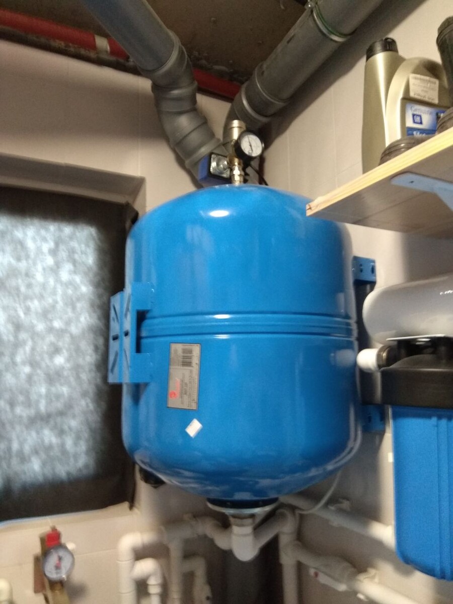 Проходной гидроаккумулятор на 100 литров расположен на стене.