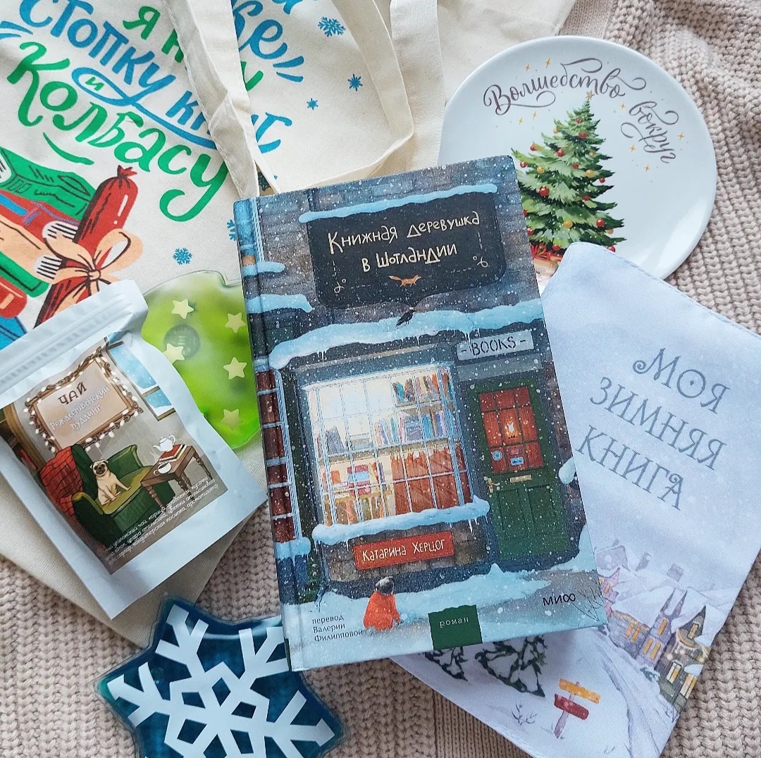 На фото подарки из бокса: шоппер, обложка для книги, грелки для рук, чай, тарелка.