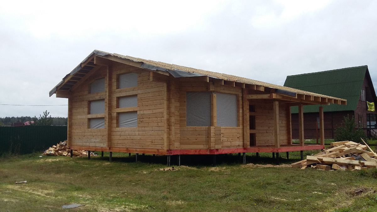 Дом из бруса под усадку, крыша временная из рубероида, месяца на 3-4.  Обратите внимание, как близко к центральной стене прорезаны окна. 