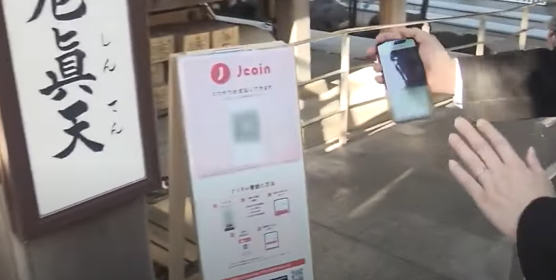 Японец сканирует код храма перед тем, как хлопнуть в ладоши и сделать пожелание на новый год