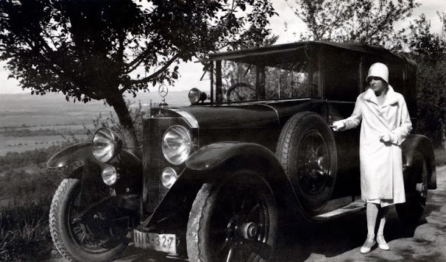 Модная дама в белом пальто, шляпе-клош, перчатках и шелковых чулках позирует с Mercedes 15/70/100 PS в сельской местности. Автомобиль с правым рулем зарегистрирован в городе Штутгарт, около 1925 года