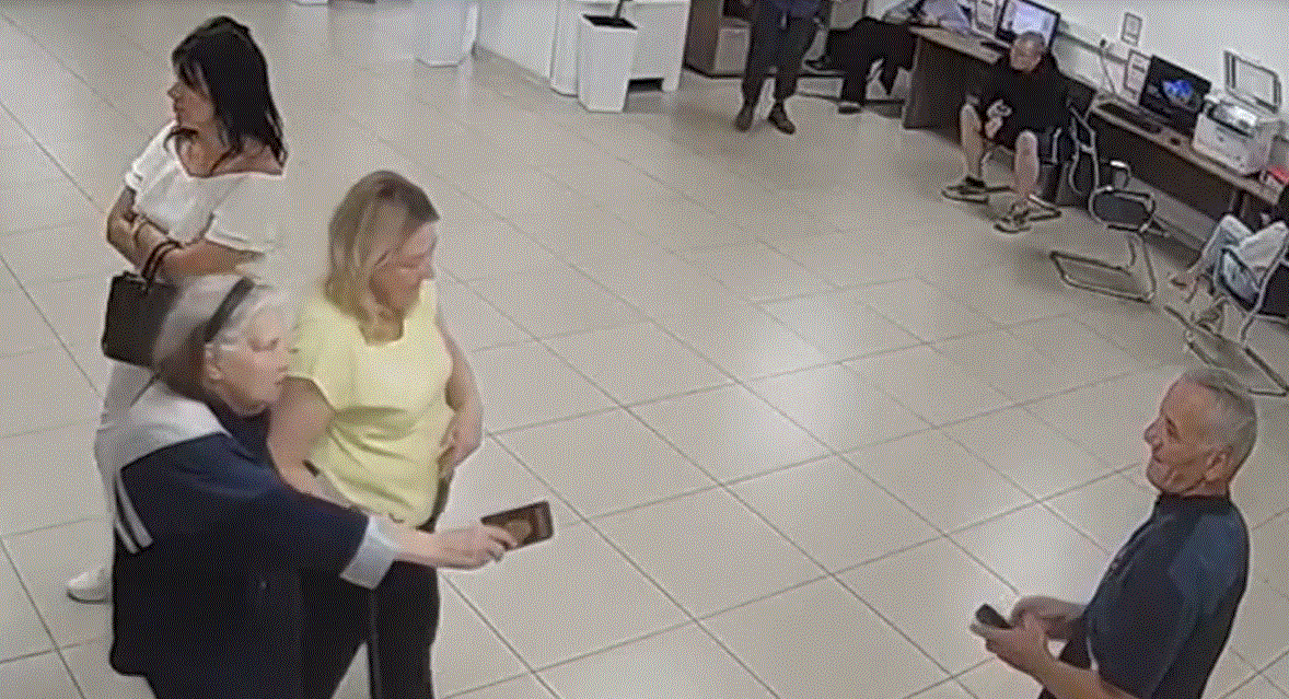 Елена ведёт Александру, которая протягивает свой новый паспорт довольному Рахмону