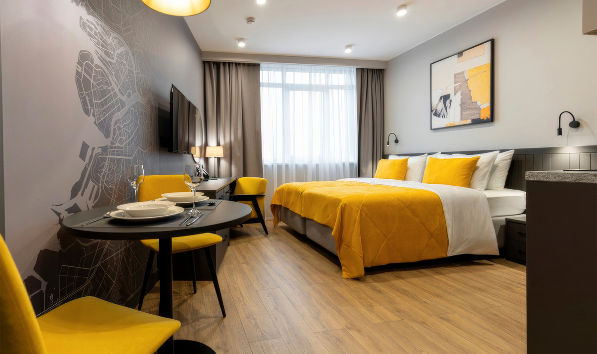 В интерьере апартаментов используются спокойные оттенки с контрастными жёлтыми деталями.