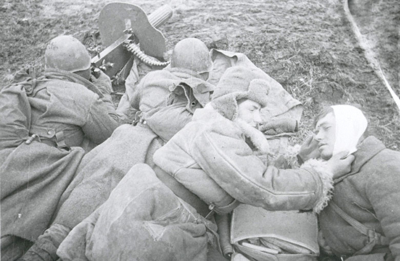 Раненный советский солдат возле пулемётного расчёта.