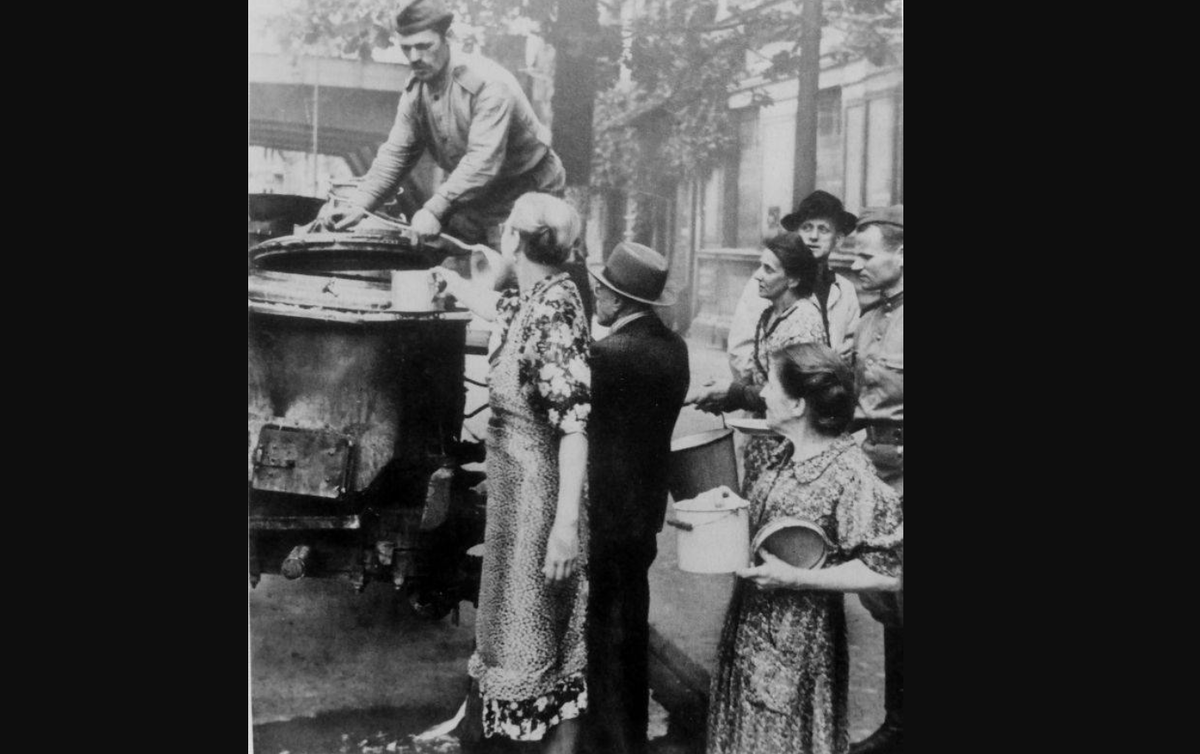 Советский солдат кормит немецких гражданских в освобожденном Берлина лета 1945-го