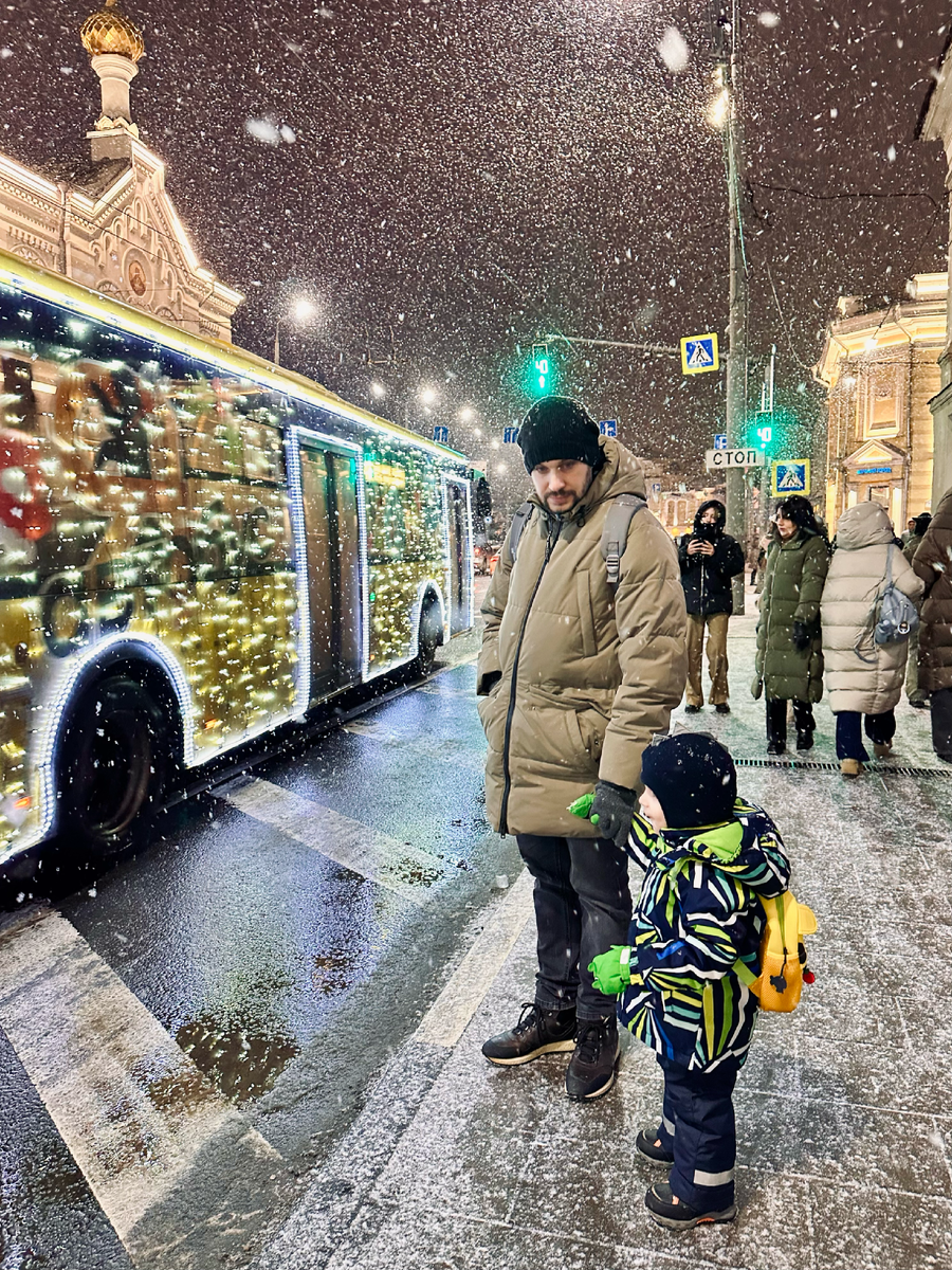 Сын и муж любуются автобусом, украшенным гирляндой, в Ярославле.
