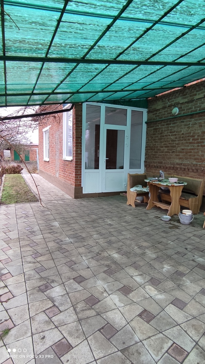 Площадка возле дома выложена плиткой, под навесом.