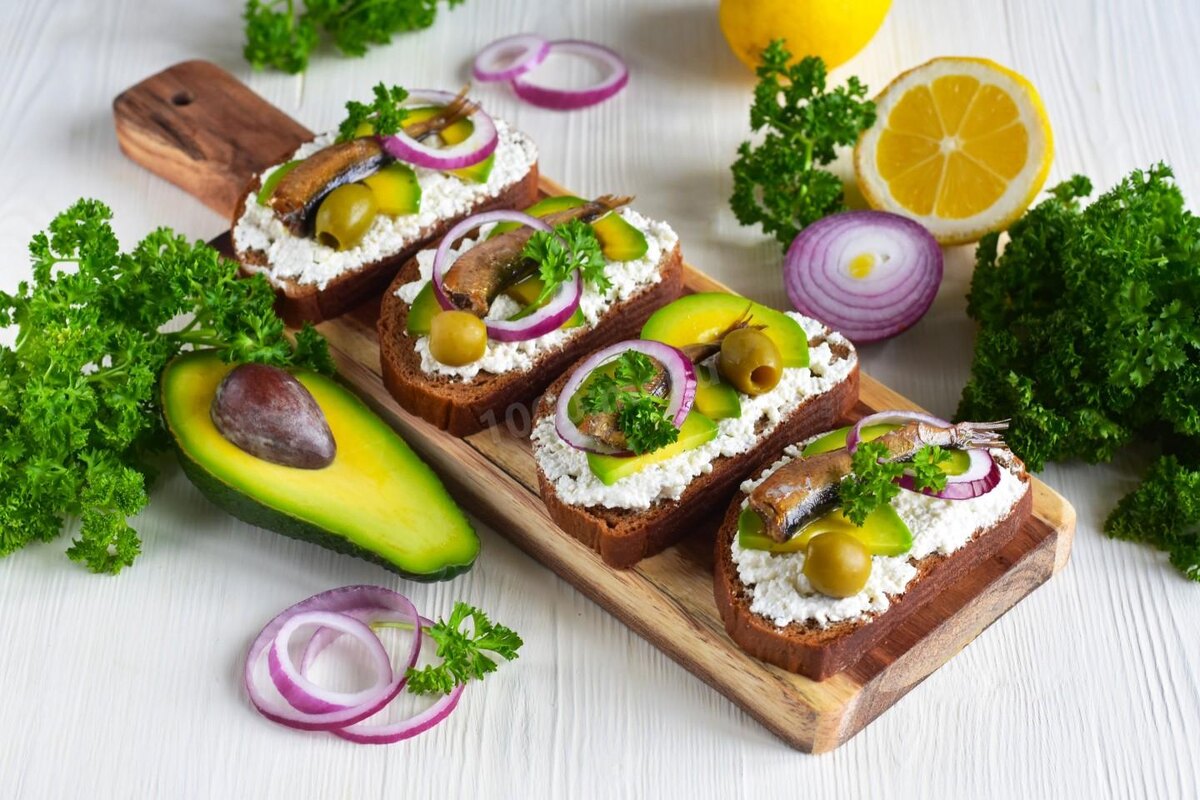 Бутерброды с авокадо: сливочный сыр, авокадо, шпроты, оливки, зелень.