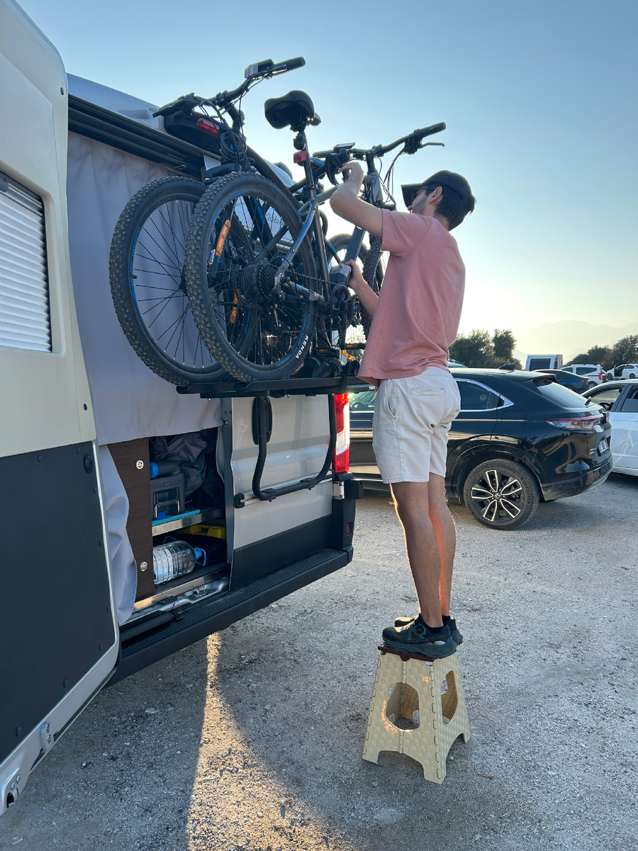 Данил закрепляет велосипеды на крепление автодома после недавней велопрогулки