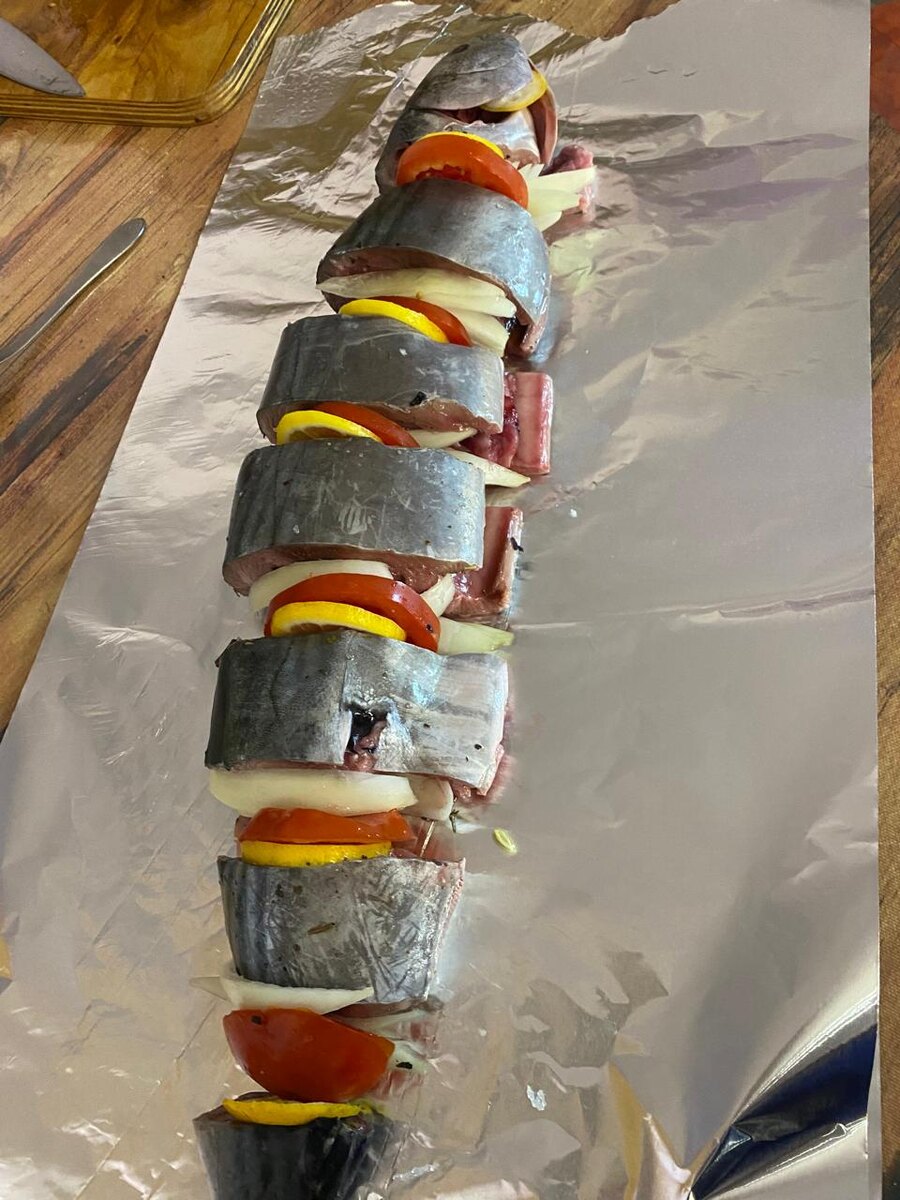 Выкладываем на фольгу, собираем и перекладываем дольками лимона, лука и помидора.