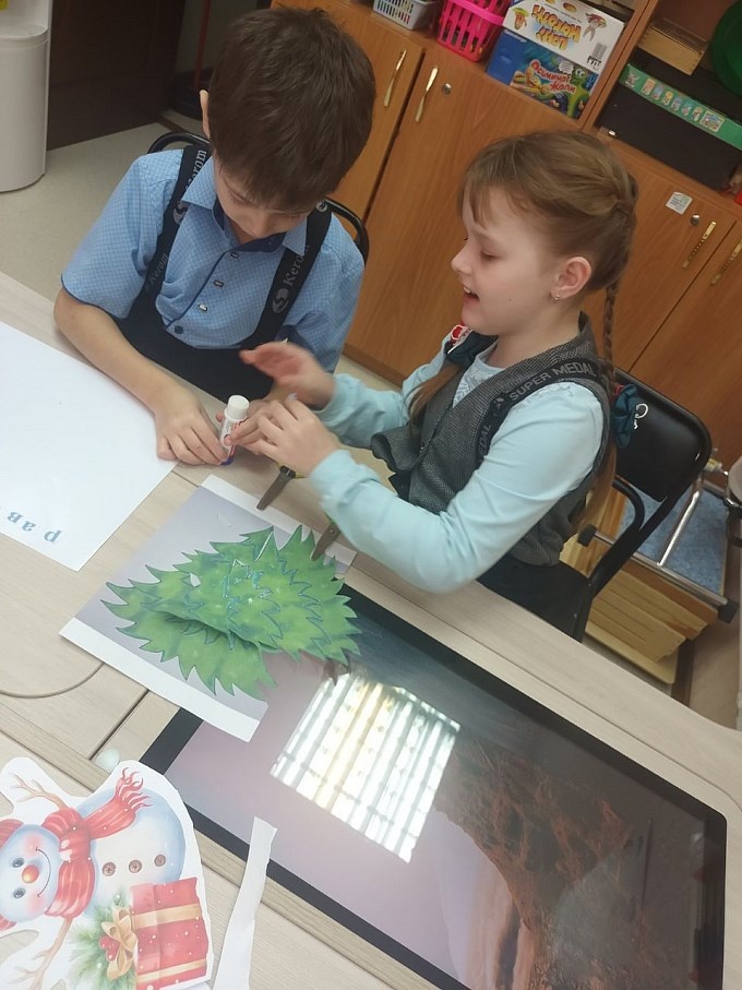 Мальчик и девочка работают над созданием стенгазеты