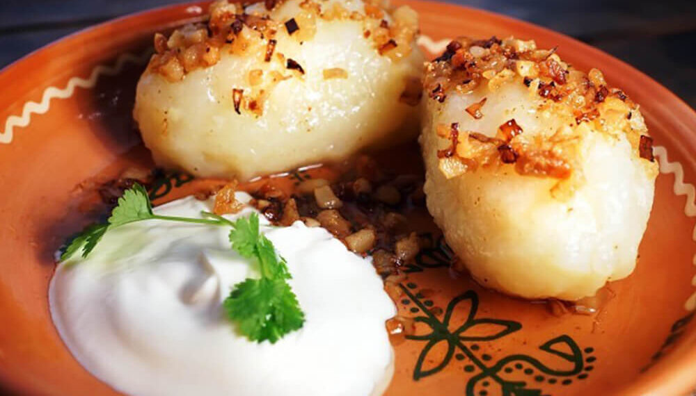 Подают цеппелины с традиционным соусом из ароматных и хрустящих шкварок