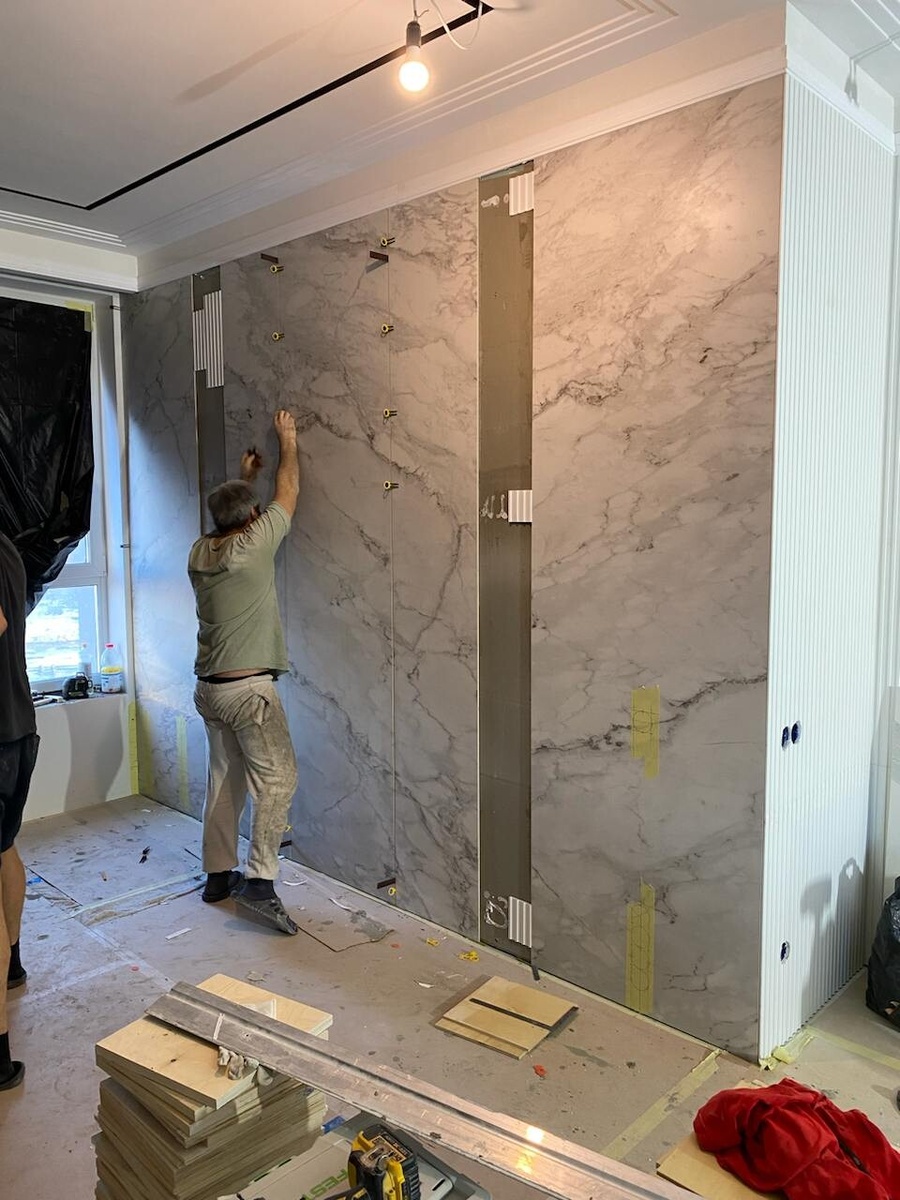 На этом фото мы уже с квалифицированными строителями доделываем ремонт. Процесс укладки на стену крупного керамогранита.