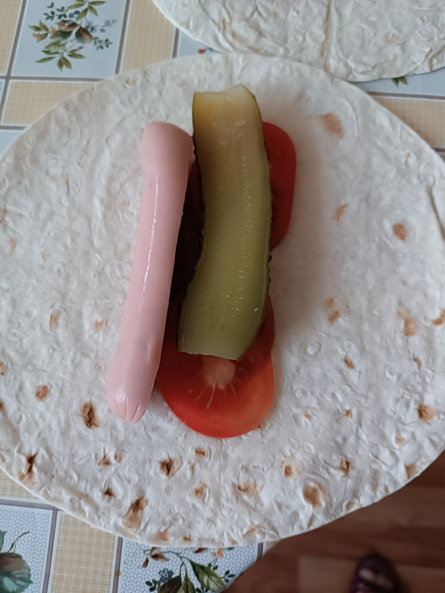 Здесь пол сосиски из рубленного мяса, огурец соленый и помидоры свежие 