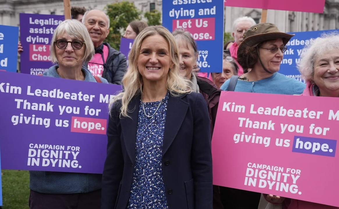 Ким Ледбитер (из партии лейбористов) - автор законопроекта со своей группой поддержки. На плакатах написано «Срасибо, что даете нам надежду». Фотография из открытого источника. 