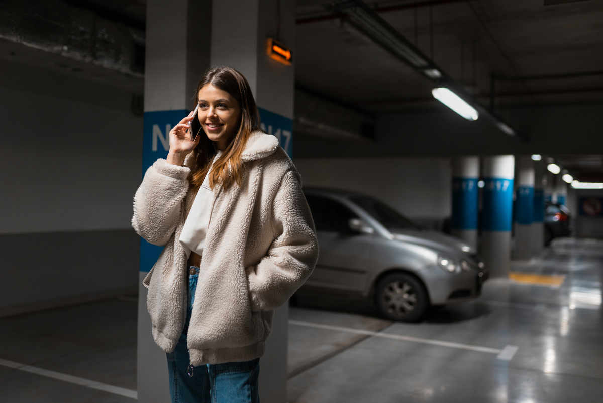    Positive fashionable girl in underground parking talking on the phone