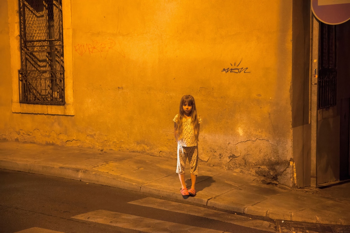 Загадочная девочка на ночной улице, создающая атмосферу уличной поэзии.