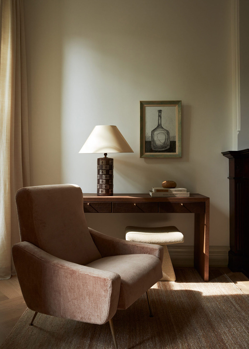 Кресло и рабочая консоль с настольной лампой.