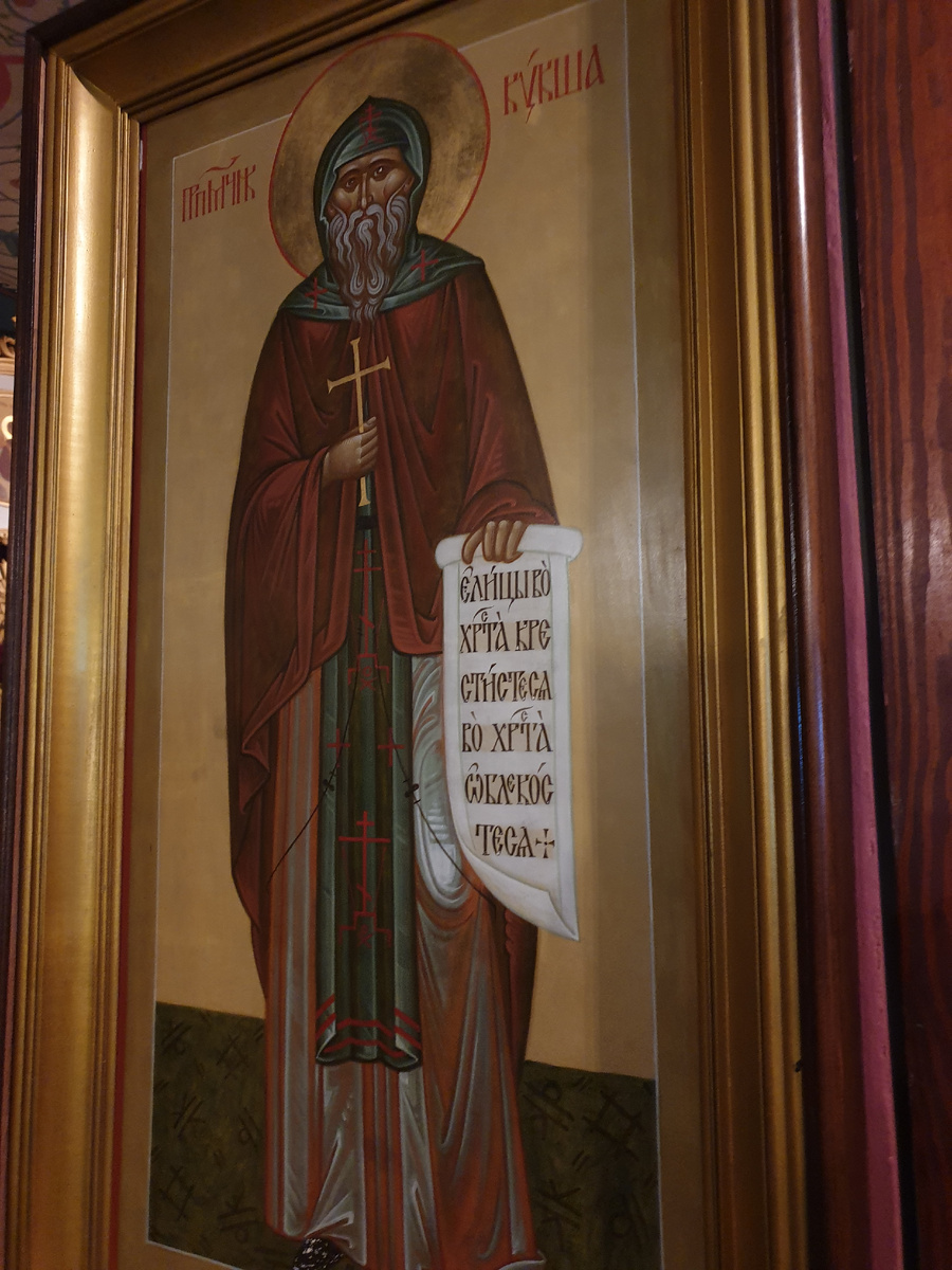 Храм Успения Пресвятой Богородицы "за верхом" г. Калуга. Икона преподобномученика Кукши на колонне трапезной части храма. Существуют разные варианты изображения Кукши в иконописи. На ростовой иконе нашего храма священномученик Кукша изображен монахом средних лет в мантии с аналавом, в схимническом куколе. У него небольшая окладистая борода с проседью. В левой руке держит развернутый свиток с текстом о крещении вятичей: "все, которые во имя Христа крестились, уподобились Христу".  В правой руке находится 4-конечный крест с удлиненной вертикальной перекладиной.