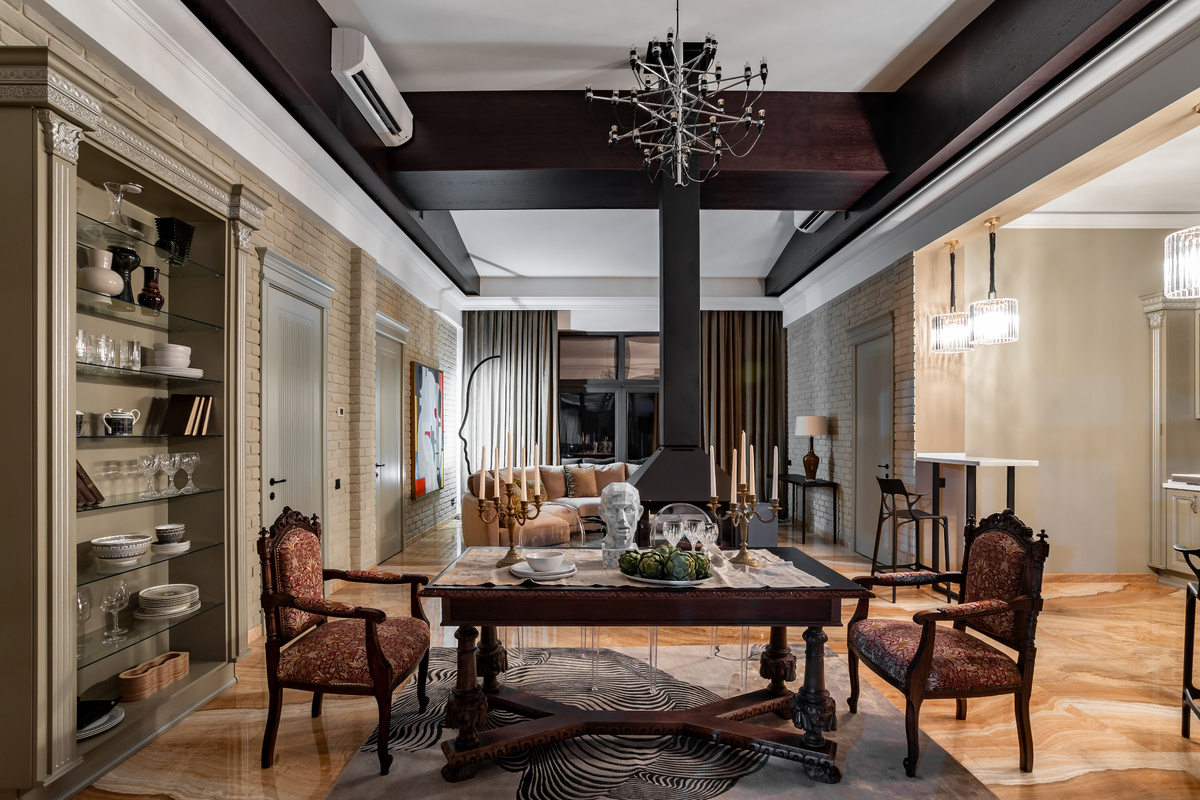 В гостиной глянцевую поверхность оникса «согревают» ковры ручной работы от Dovlet House, а фактуру кирпича на стенах смягчает благородный текстиль.  Над столом — люстра FLOS by Gino Sarfatti. 