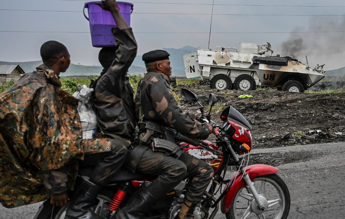 Повстанцы М23 на фоне горящего БТР миротворцев ООН. Фото из открытых источников. 