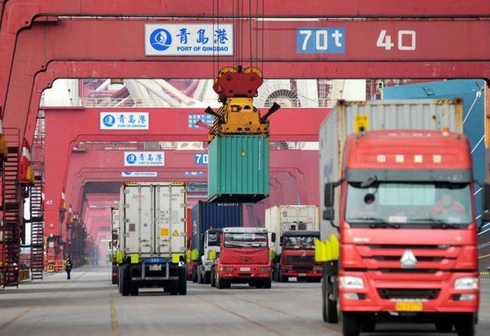 Грузовики перевозят контейнеры в порту Циндао в провинции Шаньдун, Китай. (Фото: Reuters)