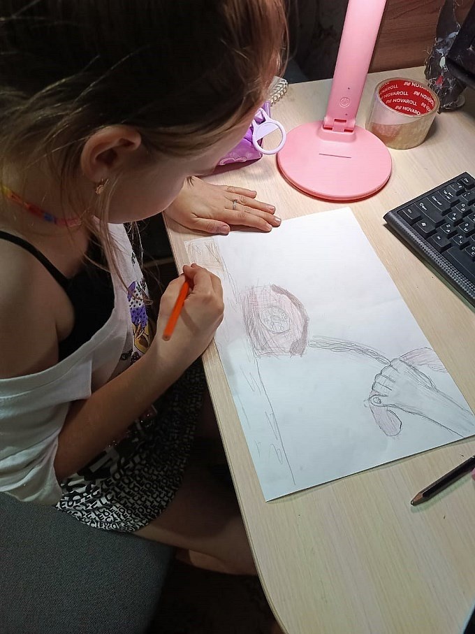 Девочка рисует карандашом на листе бумаги