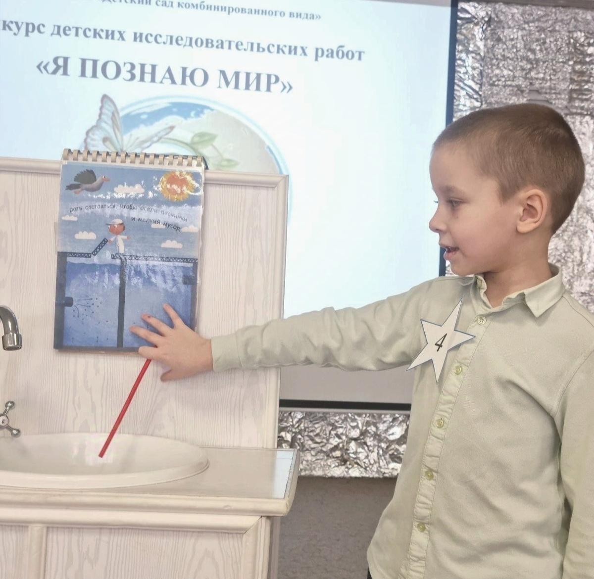 Вадим на конкурсе исследовательских работ. На пальце болячка, это он так с котом Масей играл. И палочка красная - из конструктора в группе вытащили. Другой не нашлось, а заранее не сообразили подготовить