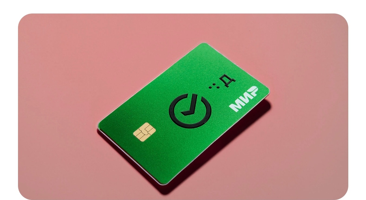 Тифлокомментарий. Изображение дебетовой карты мир. Она зелёного цвета. По центру логотип Сбера. Справа от него плоско печатная буква Д, она выпуклая, рядом с ней буква Д на Брайле