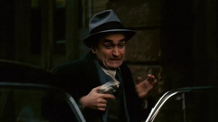 Фредо Корлеоне пытается поймать пистолет пока в его отца стреляют. Кадр из фильма "Кресный отец" 1972 г.