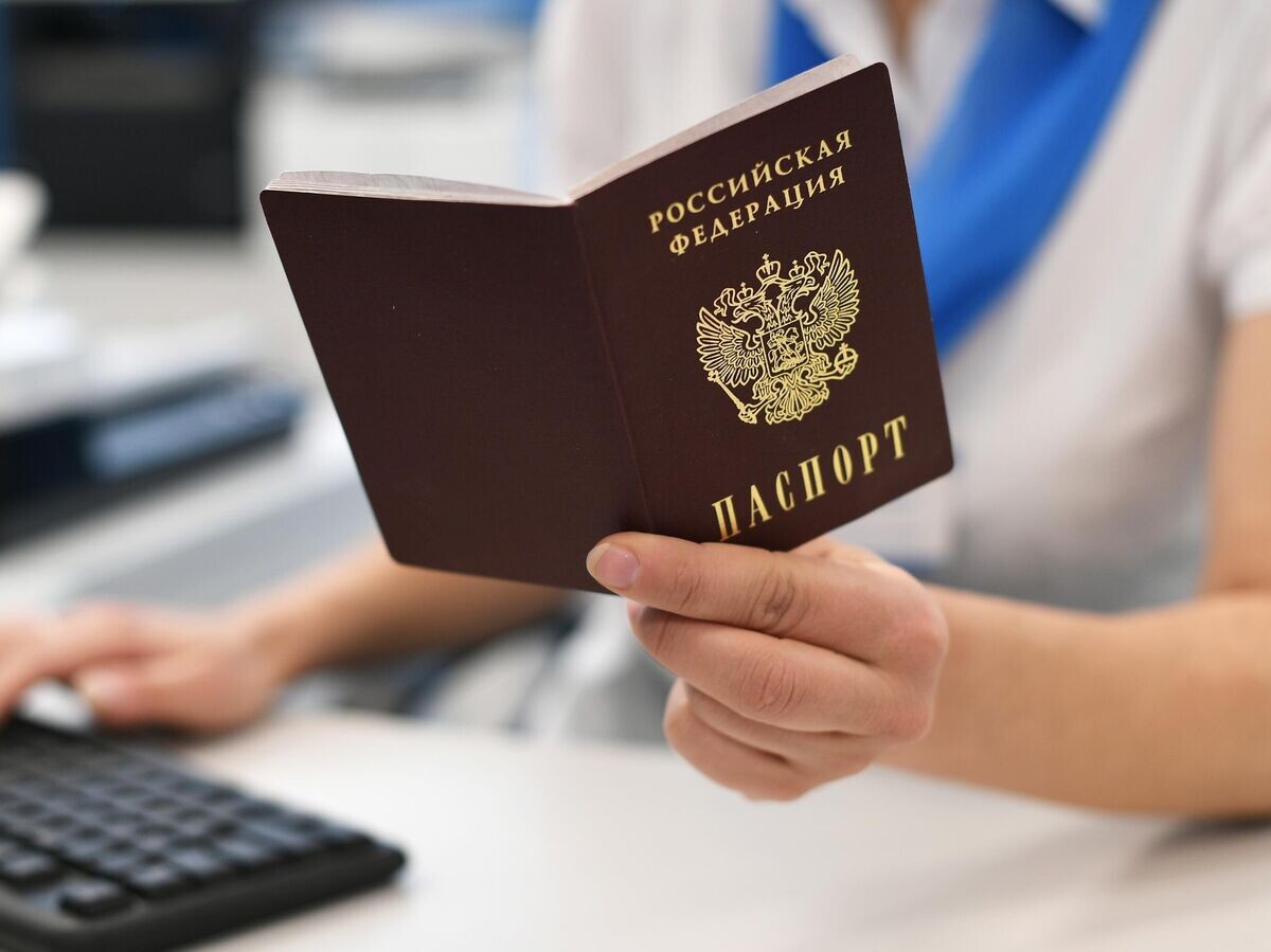    Сотрудник пенсионного фонда держит в руках паспорт РФ© РИА Новости / Максим Блинов