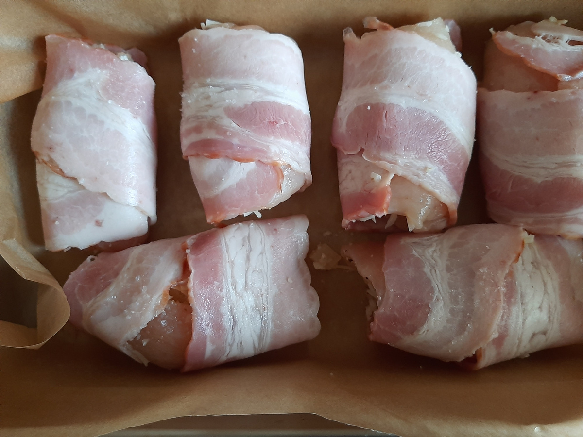 Начинку сделала из тех продуктов, что были дома: сыр на мелкой тёрке+ порезанные ананасы (были  2 кольца)+немного грецких молотых орехов. Филе куриной грудки было готово (мне нравится их подготавливать заранее, отбить, заморозить и использовать в нужный момент). Смазала небольшим количеством горчицы, солью, специями. Выложила начинку и закатала рулетиками, а сверху сыро-копченый бекон. Смешала ткемали и сметану. Кисточкой нанесла и в духовку. Рекомендую минут 20 подержать под фольгой, чтобы бекон не был сухим.