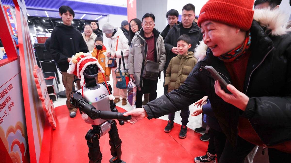    Посетительница ярмарки храма науки и технологий Весеннего фестиваля в Пекине (Китай) пожимает руку роботу в праздничной шляпе / Фото: Chen Xiaogen / VCG / Visual China Gr / ТАСС