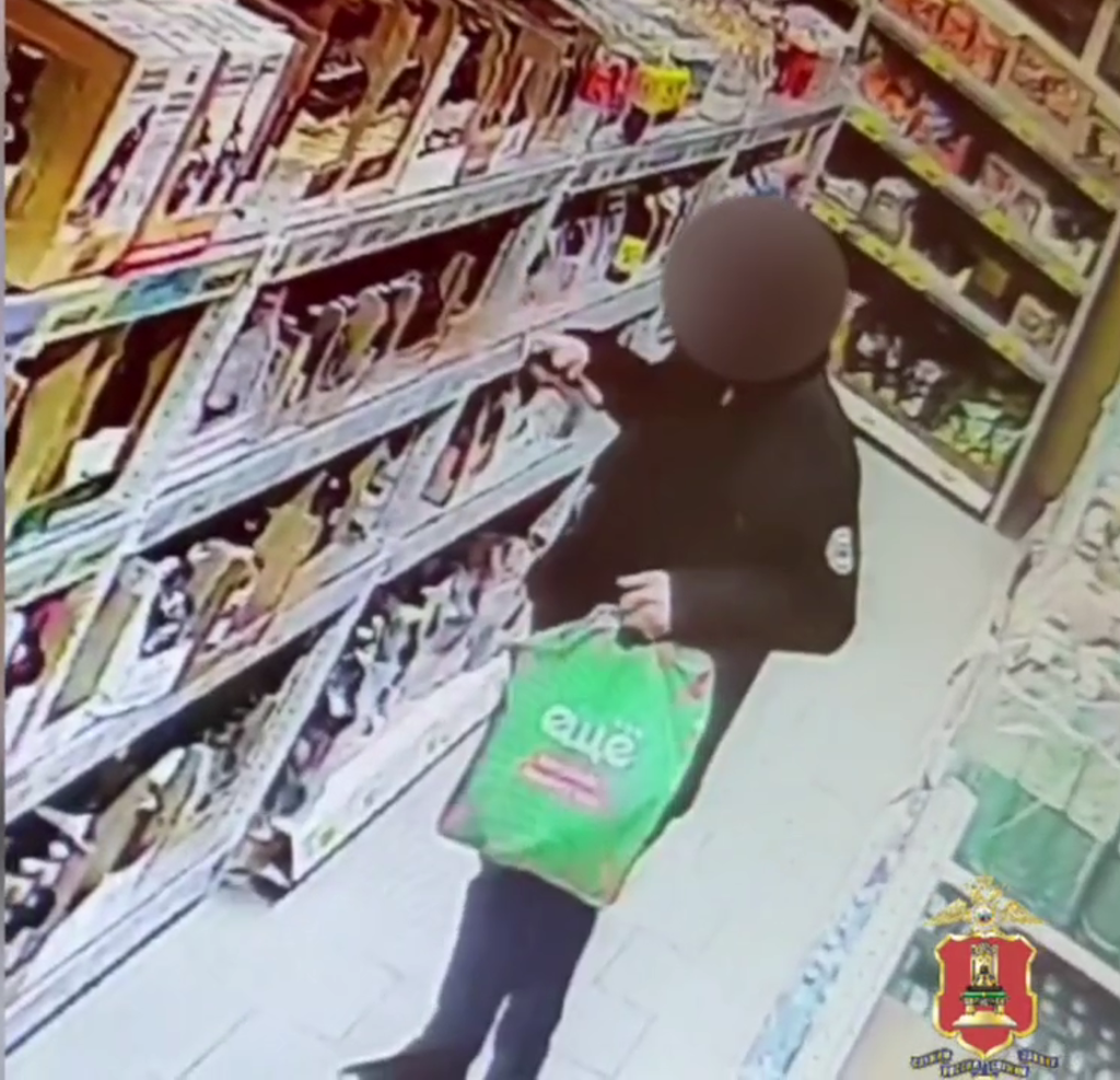 Подозреваемый примеривается, что бы еще взять с полок. Пакет с говорящим логотипом