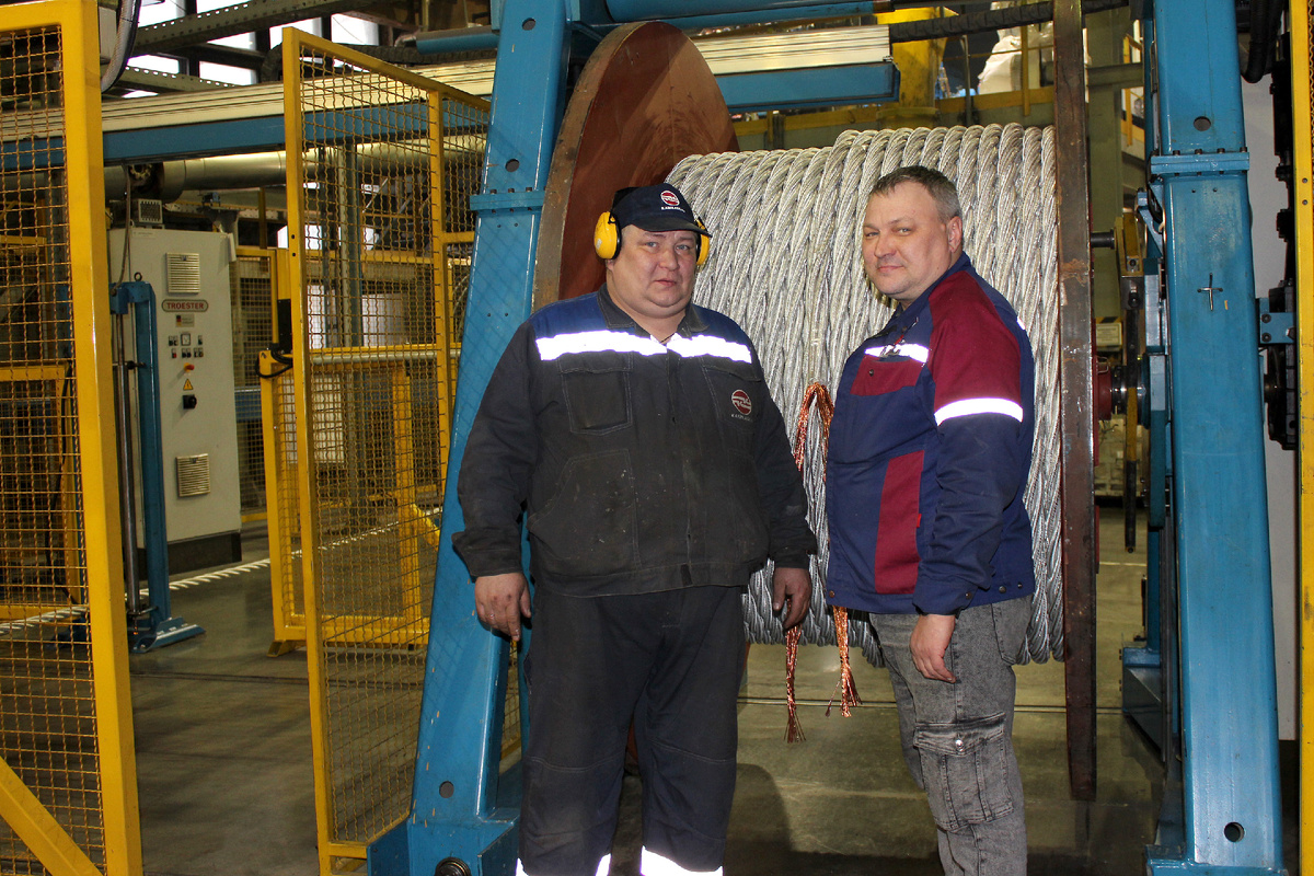 Опрессовщик В. В. Порубов накладывает оболочку на шахтный кабель. Справа на снимке старший мастер Э.В. Федосеев