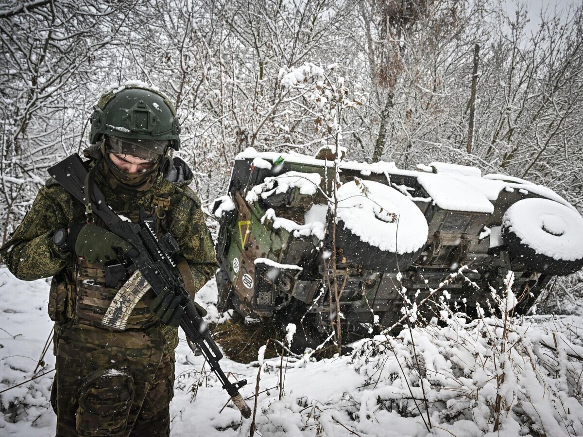 Военнослужащий ВС РФ возле подбитого бронеавтомобиля иностранного производства в Курской области© РИА Новости / Сергей Бобылев
