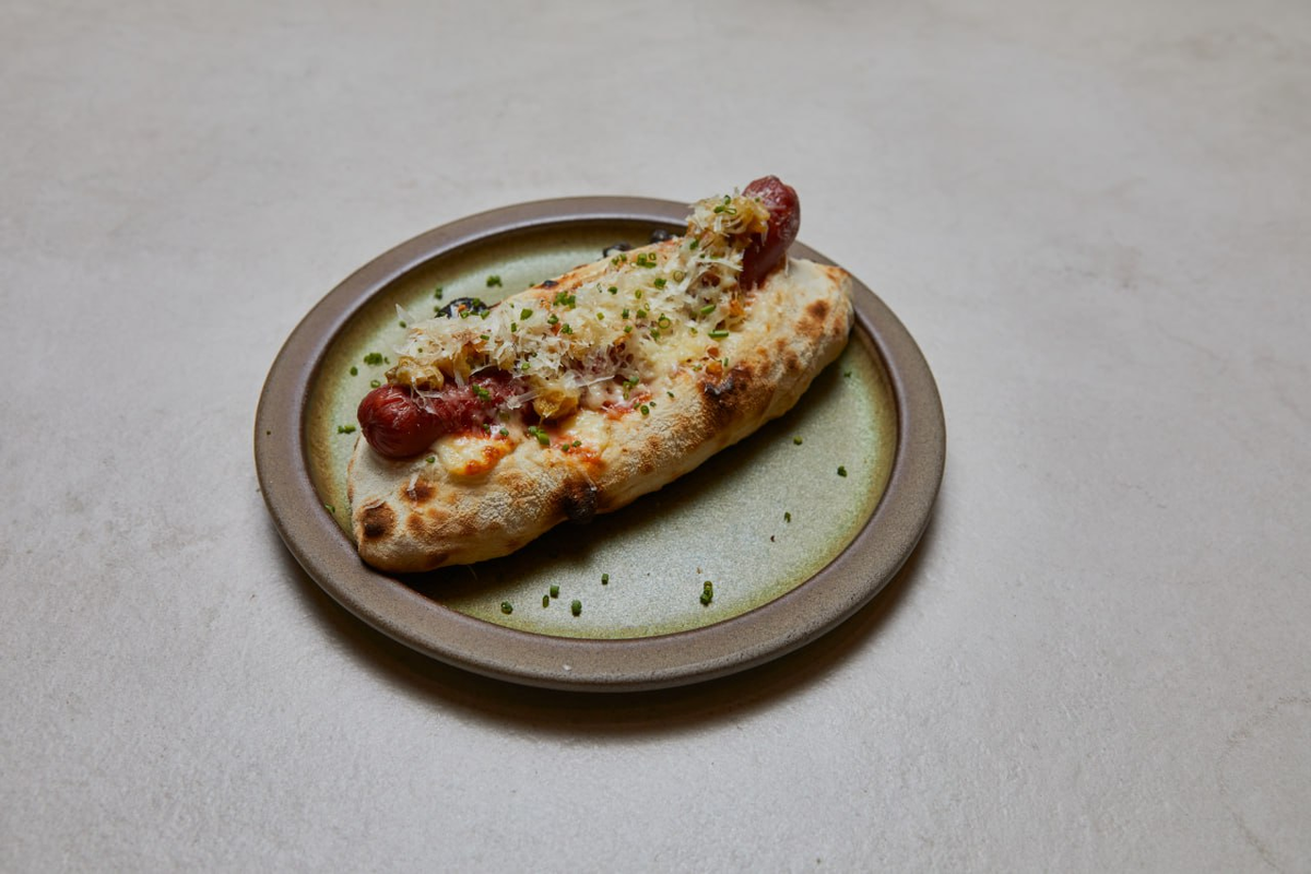 Фото: Сосиска в булочке с кунжутом, моцареллой и сибулетом в ресторане «Маргарита любит кьянти»