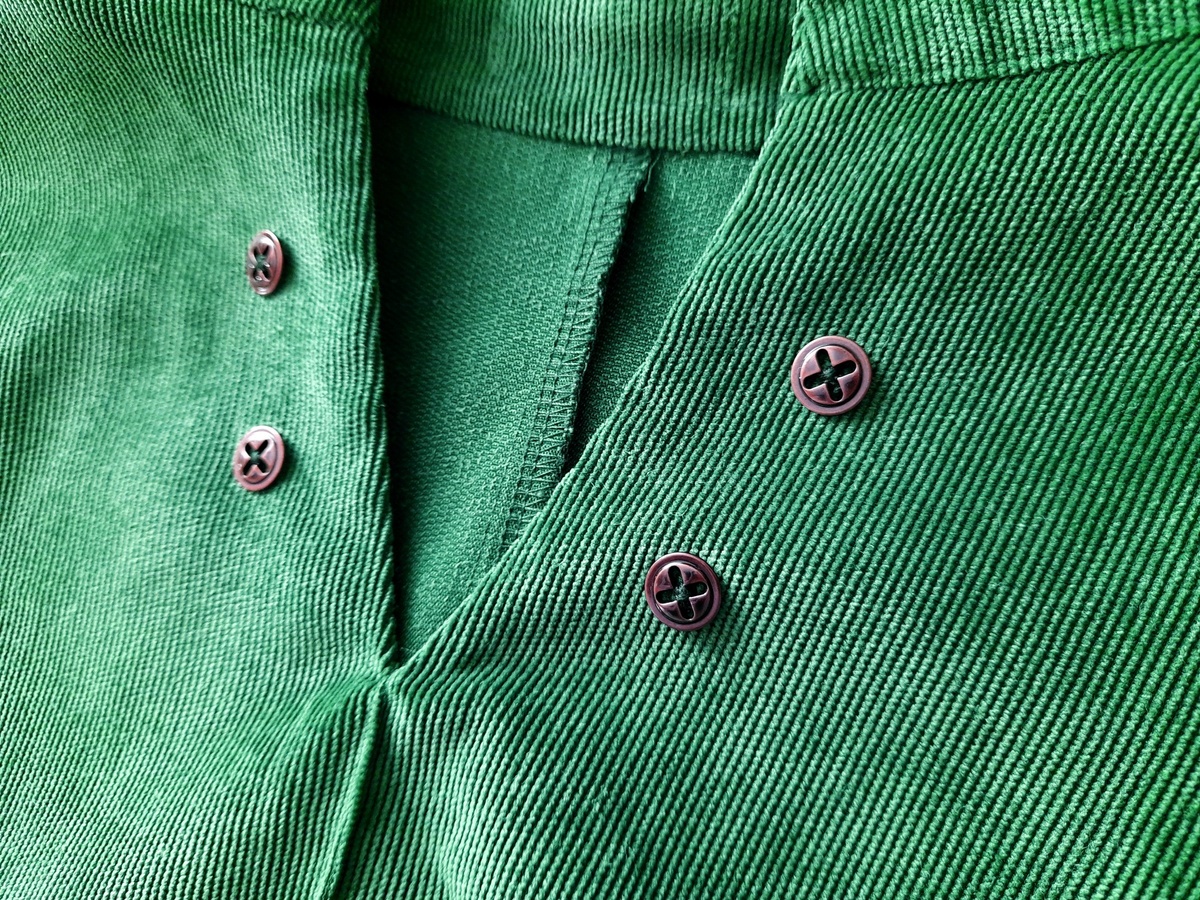 Металлические пуговицы под бронзу, пришитые к воротнику зелёного платья из микровельвета.
