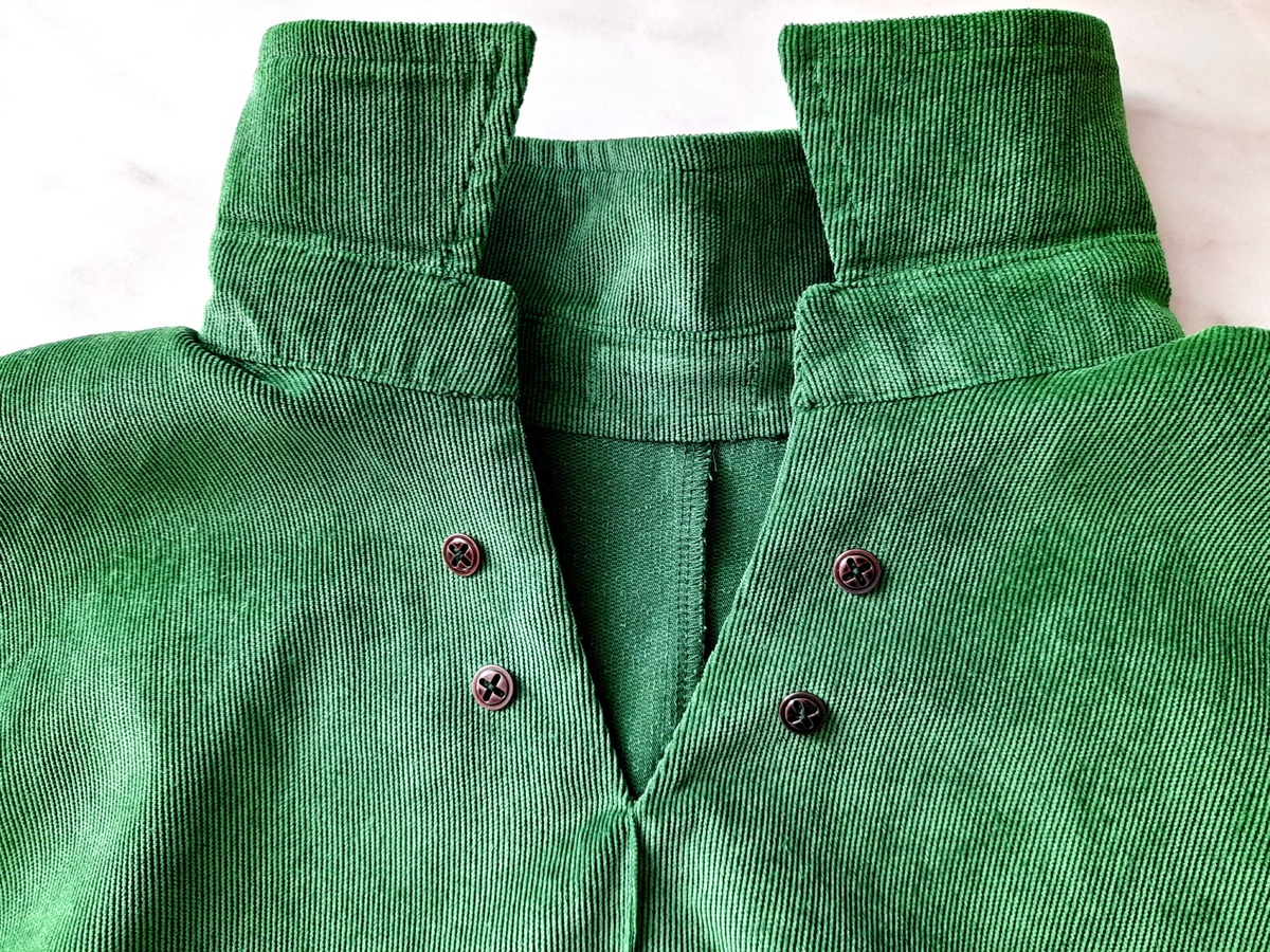 Металлические пуговицы под бронзу, пришитые к воротнику зелёного платья из микровельвета.