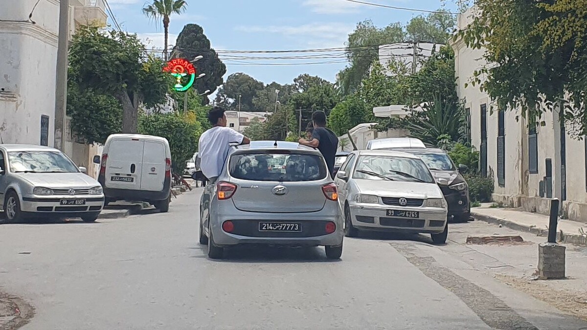 Молодёжь сидит на окнах авто в Тунисе