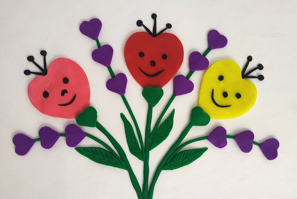 Готовый вариант аппликации из пластилина на картоне Улыбающиеся цветочки - сердечки.